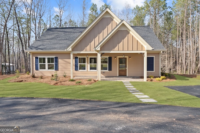 view of front of house featuring a porch, board and batten siding, a shingled roof, and a front yard