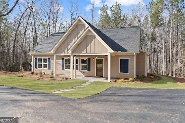 view of front of home featuring a porch, board and batten siding, a front yard, and a shingled roof