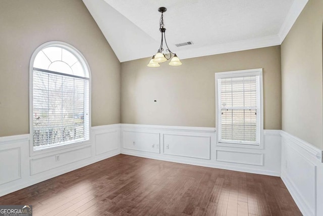 spare room with visible vents, a wainscoted wall, a notable chandelier, and dark wood finished floors