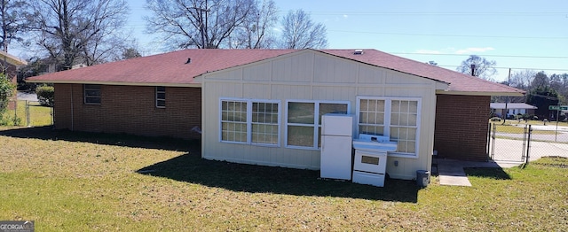 rear view of house featuring a gate, a yard, and fence