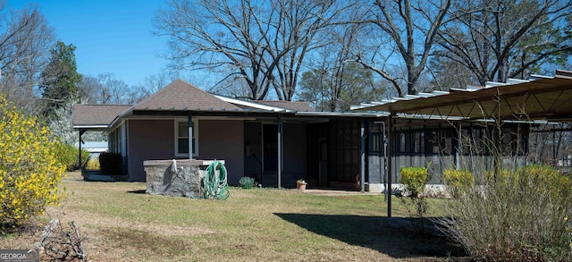 back of house featuring a lawn, a sunroom, and a shingled roof