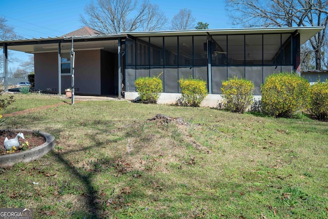 back of house with a yard, stucco siding, and a sunroom