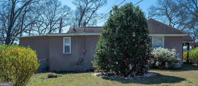 view of side of home with a shingled roof and a yard