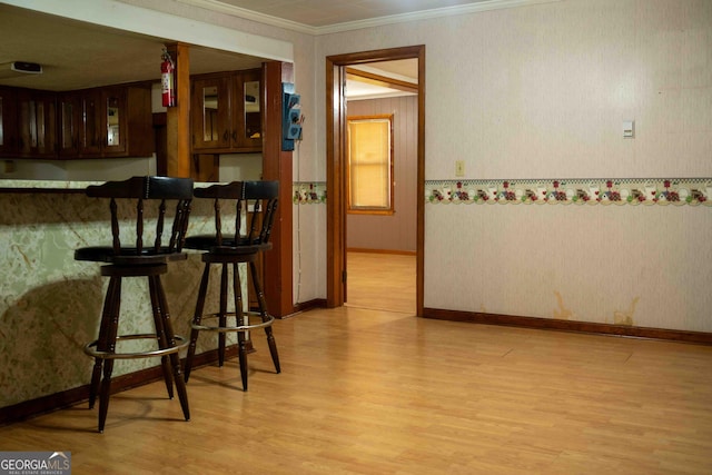 bar featuring wallpapered walls, light wood-style flooring, baseboards, and ornamental molding