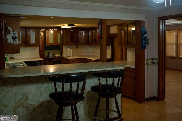 bar featuring a sink, crown molding, and light wood finished floors