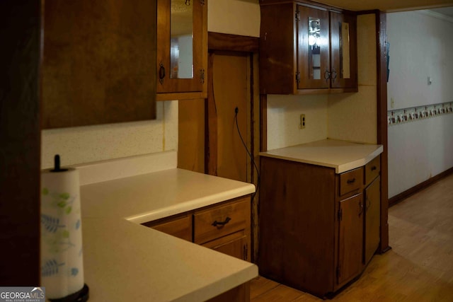 kitchen with glass insert cabinets, light wood-style flooring, and light countertops