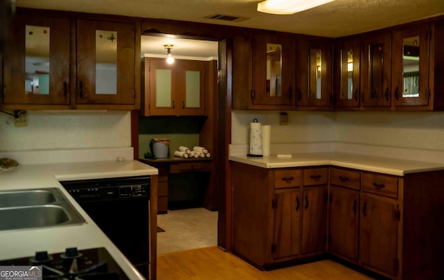 kitchen with visible vents, black appliances, light wood-style floors, light countertops, and glass insert cabinets