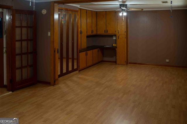 kitchen with brown cabinets, dark countertops, a ceiling fan, and light wood finished floors