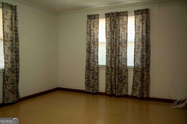 unfurnished room featuring tile patterned floors, baseboards, a healthy amount of sunlight, and crown molding