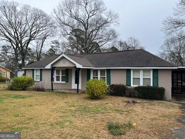 single story home with a shingled roof, a front lawn, and stucco siding