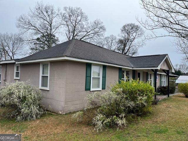 view of home's exterior with a yard and roof with shingles