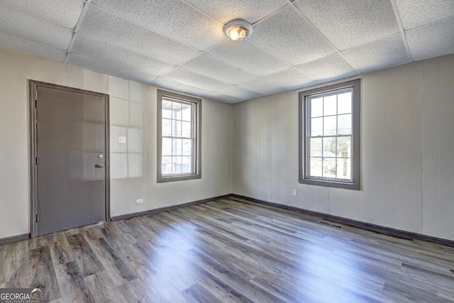 empty room featuring wood finished floors, visible vents, and a drop ceiling