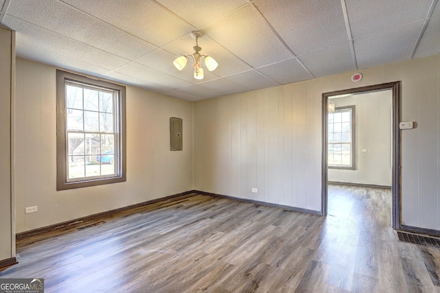 spare room with electric panel, wood finished floors, baseboards, and a paneled ceiling