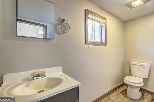 bathroom featuring vanity, toilet, wood finished floors, and baseboards