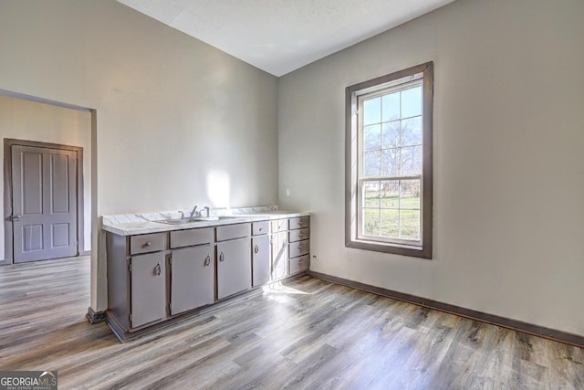 interior space with light wood-style flooring, baseboards, and a sink