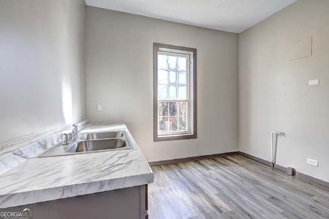 kitchen with light countertops, light wood-style floors, baseboards, and a sink