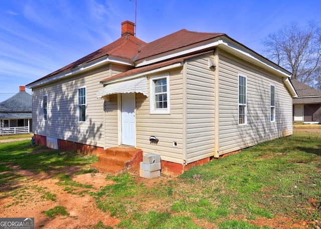 rear view of property featuring a yard and a chimney