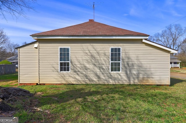 view of property exterior featuring a yard and roof with shingles