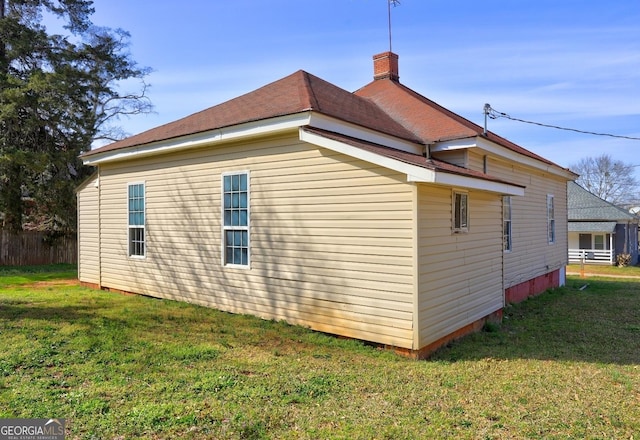 view of property exterior featuring a chimney, a yard, and fence