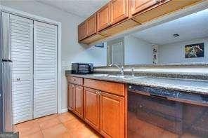 kitchen featuring light tile patterned flooring, brown cabinets, and a sink