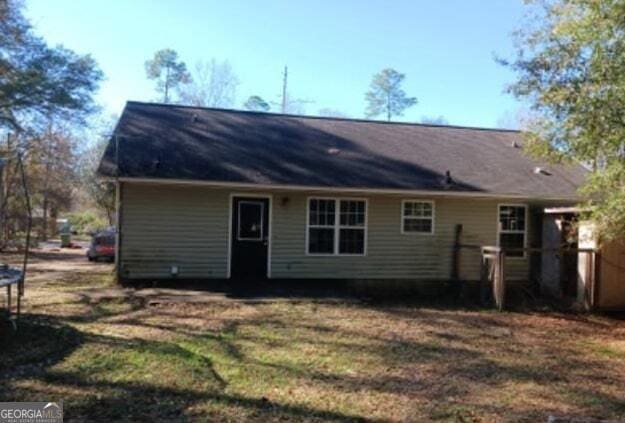 back of property with a trampoline and a yard