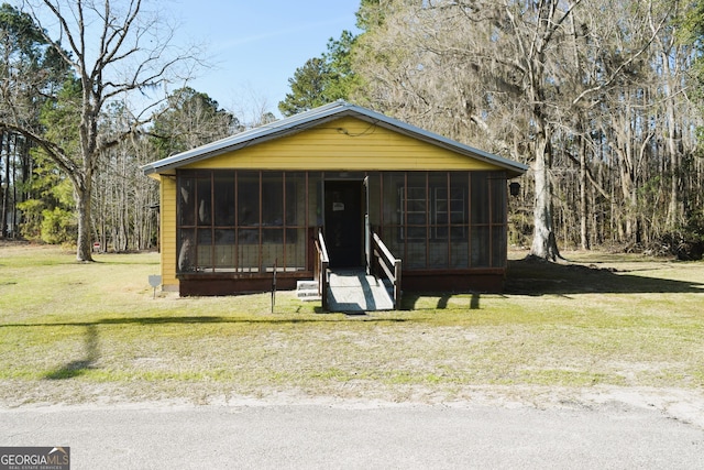 view of front of house with a front yard and a sunroom