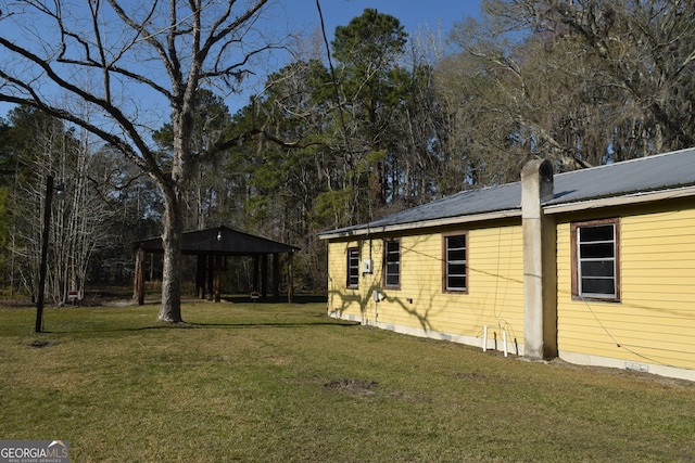 view of side of home featuring metal roof and a lawn