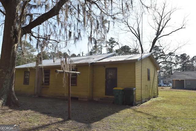 back of house featuring entry steps, a yard, central AC, and metal roof