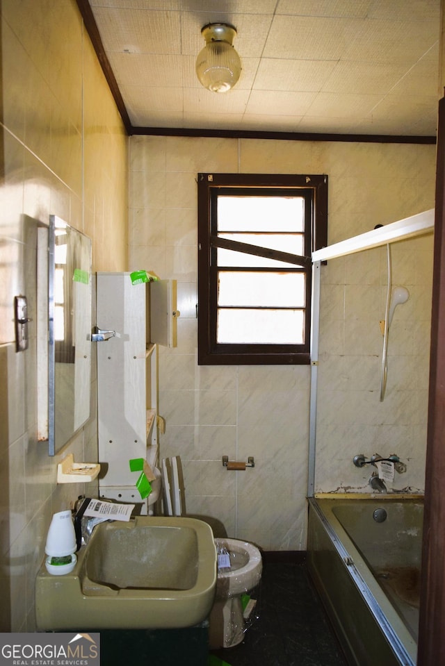 bathroom with tile walls, shower / washtub combination, crown molding, and a sink