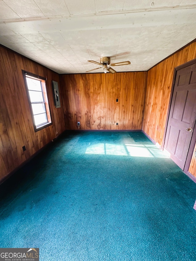 carpeted empty room featuring wood walls and ceiling fan