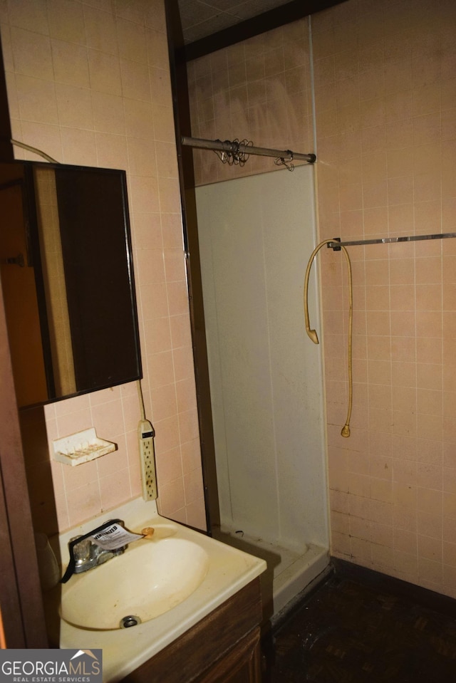 full bath featuring vanity, tile walls, and a shower stall