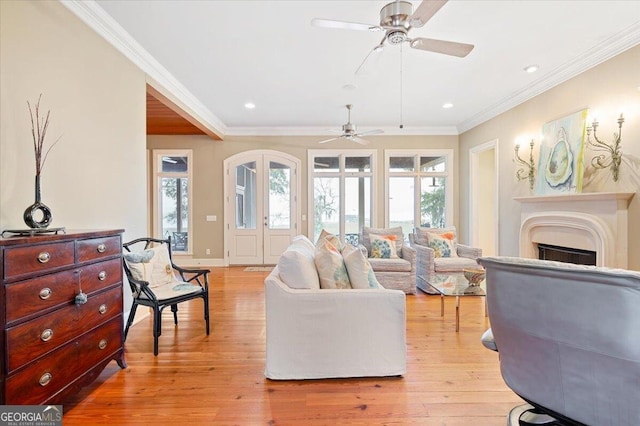 living room featuring crown molding, light wood-style flooring, and a fireplace