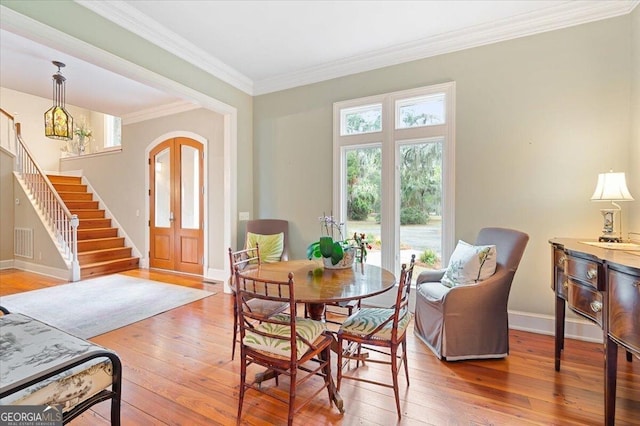 dining room featuring visible vents, hardwood / wood-style flooring, crown molding, baseboards, and stairs