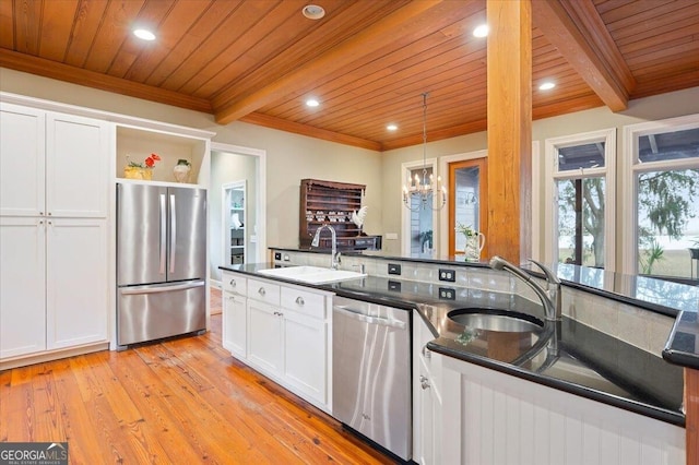 kitchen with a sink, stainless steel appliances, beamed ceiling, and white cabinetry