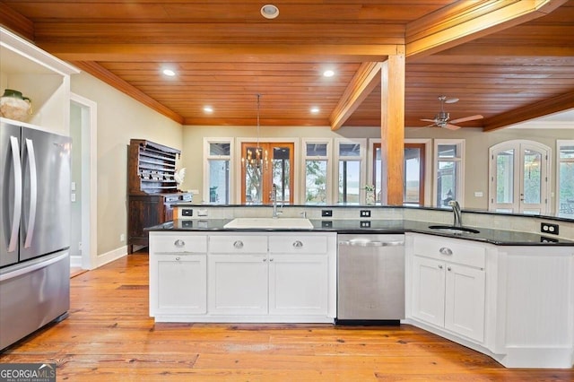 kitchen with dark countertops, ornamental molding, appliances with stainless steel finishes, white cabinetry, and a sink