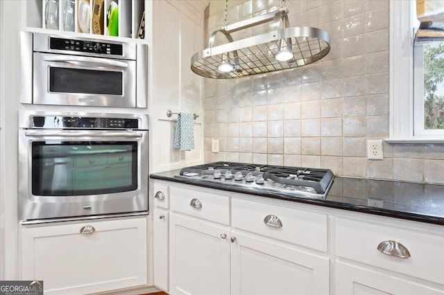 kitchen with tasteful backsplash, dark countertops, extractor fan, stainless steel appliances, and white cabinetry