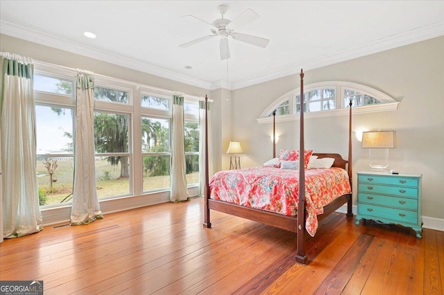 bedroom featuring multiple windows, baseboards, ornamental molding, and wood-type flooring