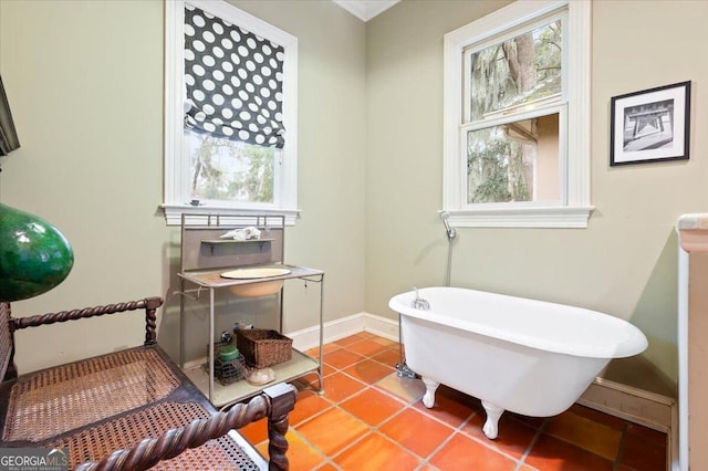 bathroom featuring tile patterned flooring, a soaking tub, a healthy amount of sunlight, and baseboards