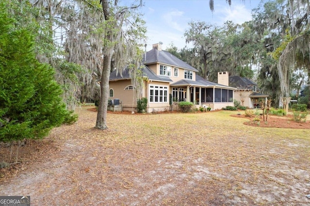 exterior space featuring a chimney, a yard, and a sunroom