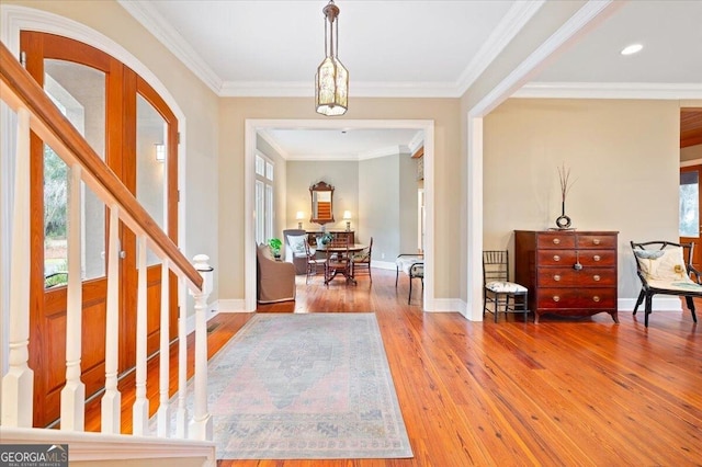 foyer entrance featuring hardwood / wood-style floors, stairs, baseboards, and ornamental molding