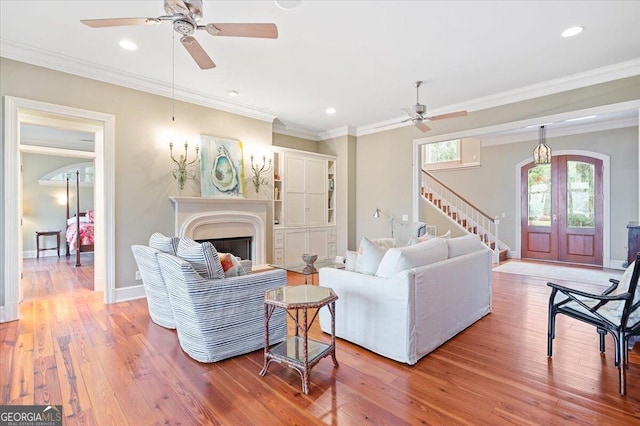 living area with light wood finished floors, recessed lighting, a fireplace, crown molding, and baseboards