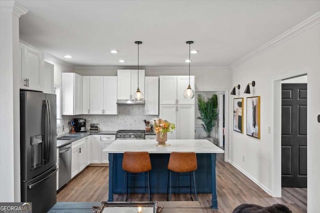 kitchen with a kitchen island, white cabinets, stainless steel appliances, and crown molding