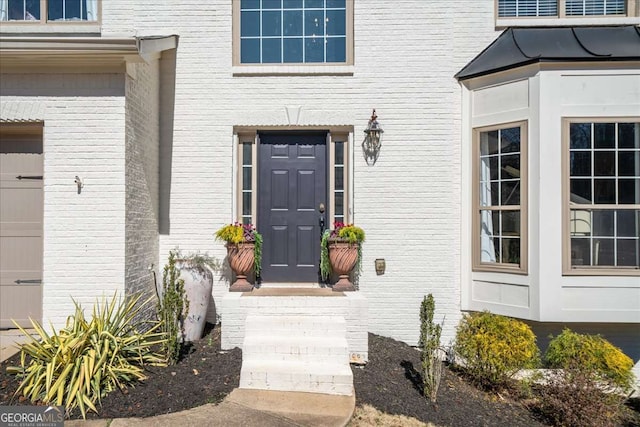 doorway to property with a garage and brick siding