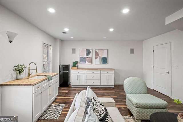 kitchen featuring visible vents, freestanding refrigerator, a sink, white cabinets, and wood counters