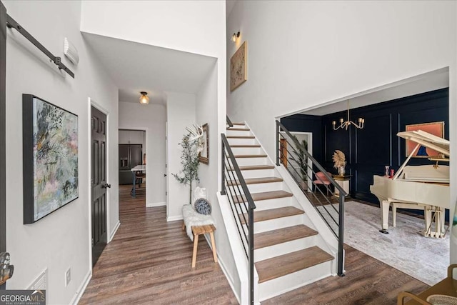 staircase featuring a notable chandelier, baseboards, and wood finished floors