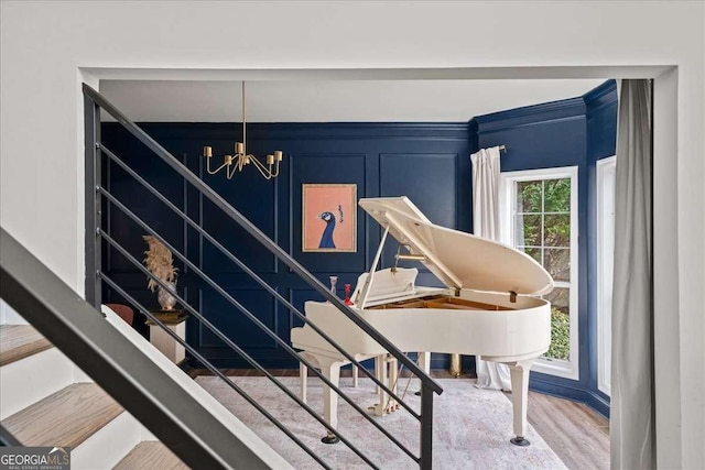 stairway with a notable chandelier, a decorative wall, and wood finished floors