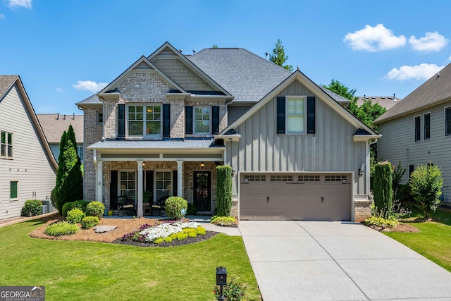 craftsman-style home with a front lawn, board and batten siding, covered porch, concrete driveway, and brick siding