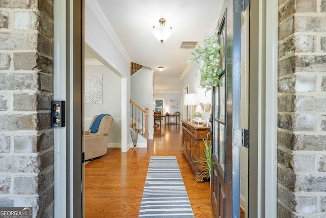 entrance foyer with visible vents, baseboards, stairway, ornamental molding, and light wood-style flooring