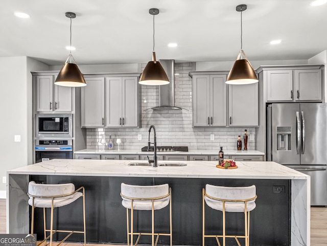 kitchen featuring tasteful backsplash, appliances with stainless steel finishes, gray cabinetry, and wall chimney range hood