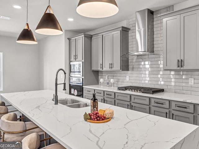 kitchen with visible vents, gray cabinets, a sink, stainless steel appliances, and wall chimney exhaust hood